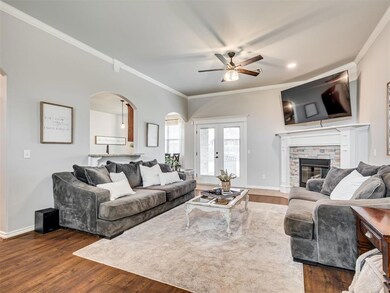 Living room with a fireplace, ceiling fan, crown m