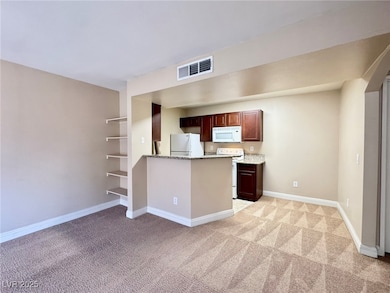 Kitchen with white appliances, light carpet, baseb