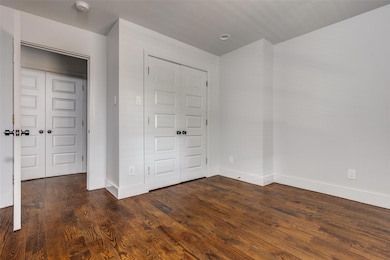 Unfurnished bedroom with dark wood-type flooring a