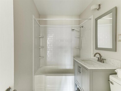 Full bathroom with tiled shower / bath combo, toilet, and vanity