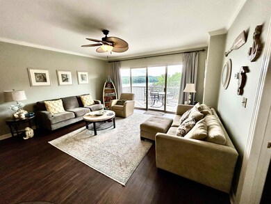 Living area featuring crown molding, a ceiling fan, wood finished floors, and a water view