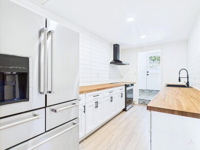 Kitchen featuring high end white fridge, wood cou