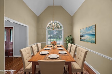 Dining area with dark wood-style floors, a chandelier, and high vaulted ceiling