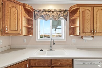 Kitchen with open shelves, light countertops, white dishwasher, and brown cabinetry