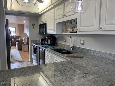 Kitchen with white cabinetry, sink, light hardwood / wood-style floors, stone countertops, and black appliances