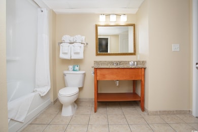Bathroom with baseboards, vanity, toilet, and tile