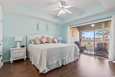 Bedroom with dark wood-style floors, a tray ceilin