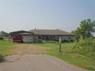 View of front of home featuring driveway, a carport, and stone siding