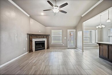 Unfurnished living room with vaulted ceiling, ceiling fan, a fireplace, a chandelier, and light wood-type flooring