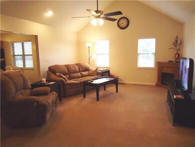 The living room has a cathedral ceiling with ceiling fan and recessed lighting and features an arched opening to the eat-in kitchen.