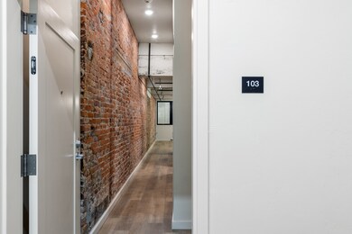 Corridor featuring hardwood / wood-style flooring, a towering ceiling, and brick wall