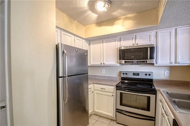 Kitchen with white cabinetry, appliances with stai