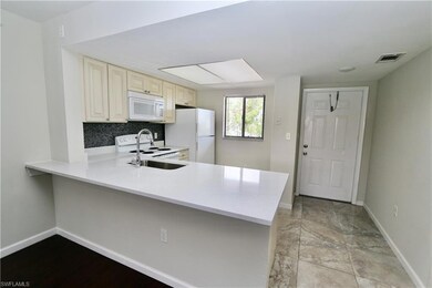 Kitchen with cream cabinets, white appliances, baseboards, and light countertops
