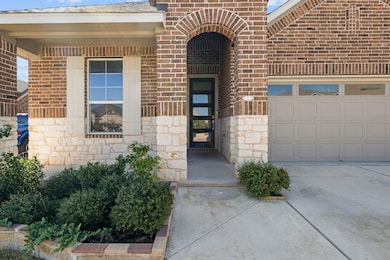 Property entrance featuring concrete driveway, stone siding, brick siding, an attached garage, and a shingled roof