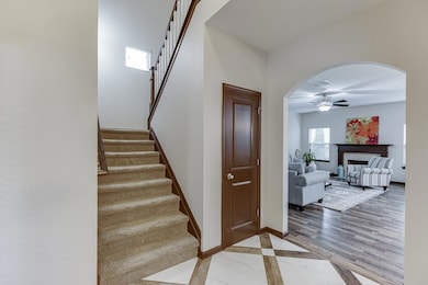 Staircase with ceiling fan, arched walkways, and baseboards