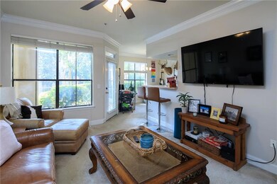 Living area featuring ornamental molding, light carpet, and ceiling fan