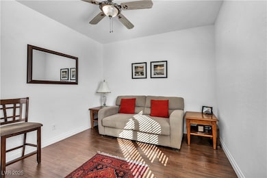 Living area featuring dark wood-style flooring and ceiling fan