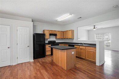 Kitchen featuring black appliances, a kitchen island, dark wood-type flooring, a textured ceiling, and dark countertops