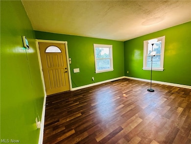 Empty room with a textured ceiling and dark hardwood flooring
