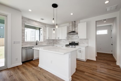 Kitchen with light countertops, wall chimney exha