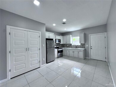 Kitchen featuring light countertops, stainless steel appliances, baseboards, decorative backsplash, and a sink