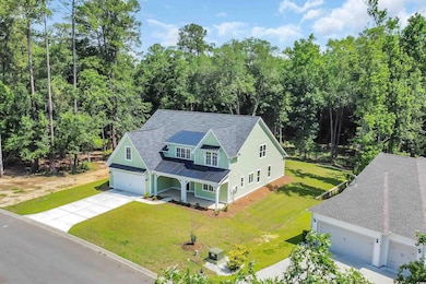 View of front of property featuring covered porch, driveway, a standing seam roof, metal roof, and a front yard