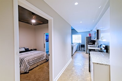 Hall featuring concrete floors, baseboards, and recessed lighting