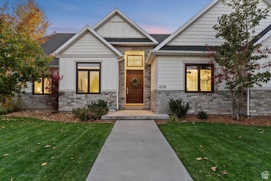 Exterior entry at dusk featuring board and batten siding, stone siding, and a yard