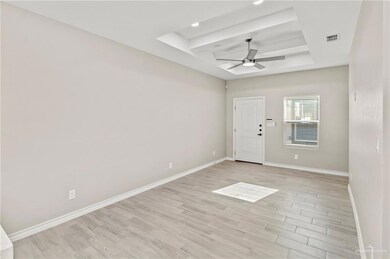 Spare room featuring light wood-type flooring, beam ceiling, ceiling fan, and a tray ceiling