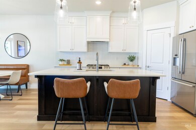 Kitchen with stainless steel fridge, a breakfast bar area, a center island with sink, light countertops, and recessed lighting
