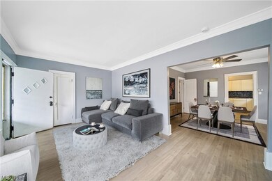 Living room virtually staged featuring ceiling fan, light hardwood flooring, and crown molding