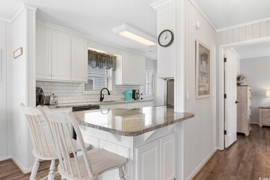 Kitchen with a breakfast bar, white cabinetry, lig