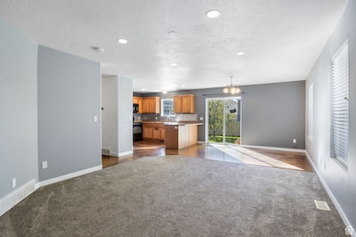 Unfurnished living room with a chandelier, dark carpet, recessed lighting, and a textured ceiling