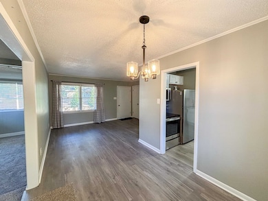 Unfurnished dining area with crown molding, a chandelier, wood finished floors, and a textured ceiling