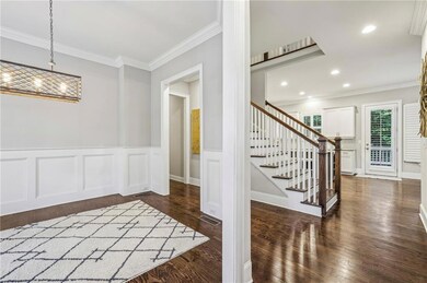 Entrance foyer featuring crown molding, dark wood-style floors, stairway, recessed lighting, and a wainscoted wall