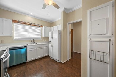 Kitchen with white cabinetry, appliances with stai