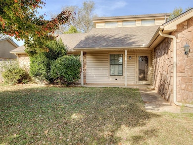 View of front facade featuring stone siding, a front yard, covered porch, and roof with shingles