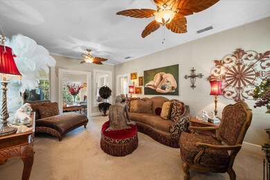 Carpeted living room with ornamental molding and ceiling fan