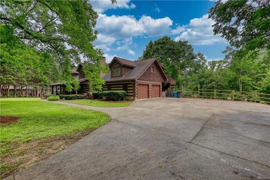View of home's exterior featuring driveway, log exterior, and a chimney