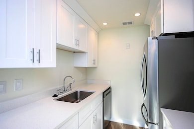 Kitchen featuring stainless steel appliances, recessed lighting, white cabinets, and light stone countertops