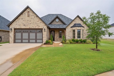 View of front of home featuring brick siding, a porch, a front lawn, driveway, and a garage