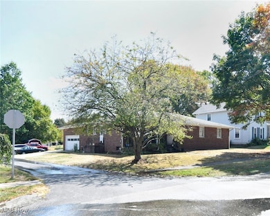 View of front facade featuring asphalt driveway, brick siding, a front yard, and a garage