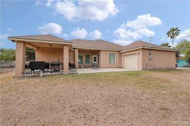 Rear view of property with stucco siding, fence, an attached garage, a yard, and a patio area