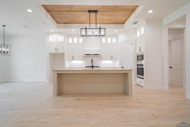 Kitchen featuring a kitchen island with sink, a tr