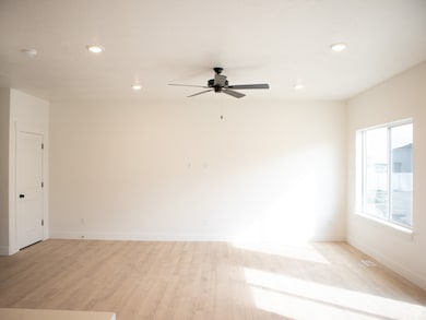 Great room off of kitchen and dining area with laminate flooring and ceiling fan.