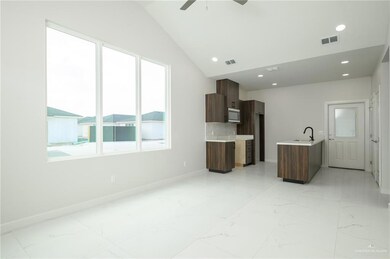 Unfurnished living room featuring plenty of natural light, a sink, light marble finish floors, lofted ceiling, and recessed lighting