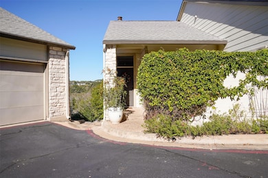Doorway to property with a shingled roof and ston