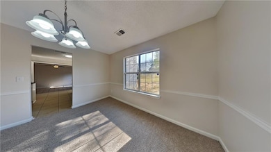 Carpeted spare room with a chandelier, baseboards, a textured ceiling, and a ceiling fan
