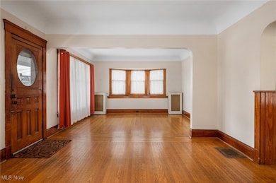 Foyer entrance with wood-type flooring, arched walkways, and radiator