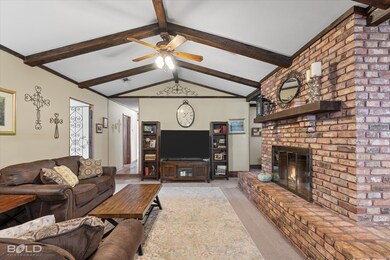 Carpeted living area with a brick fireplace and a ceiling fan